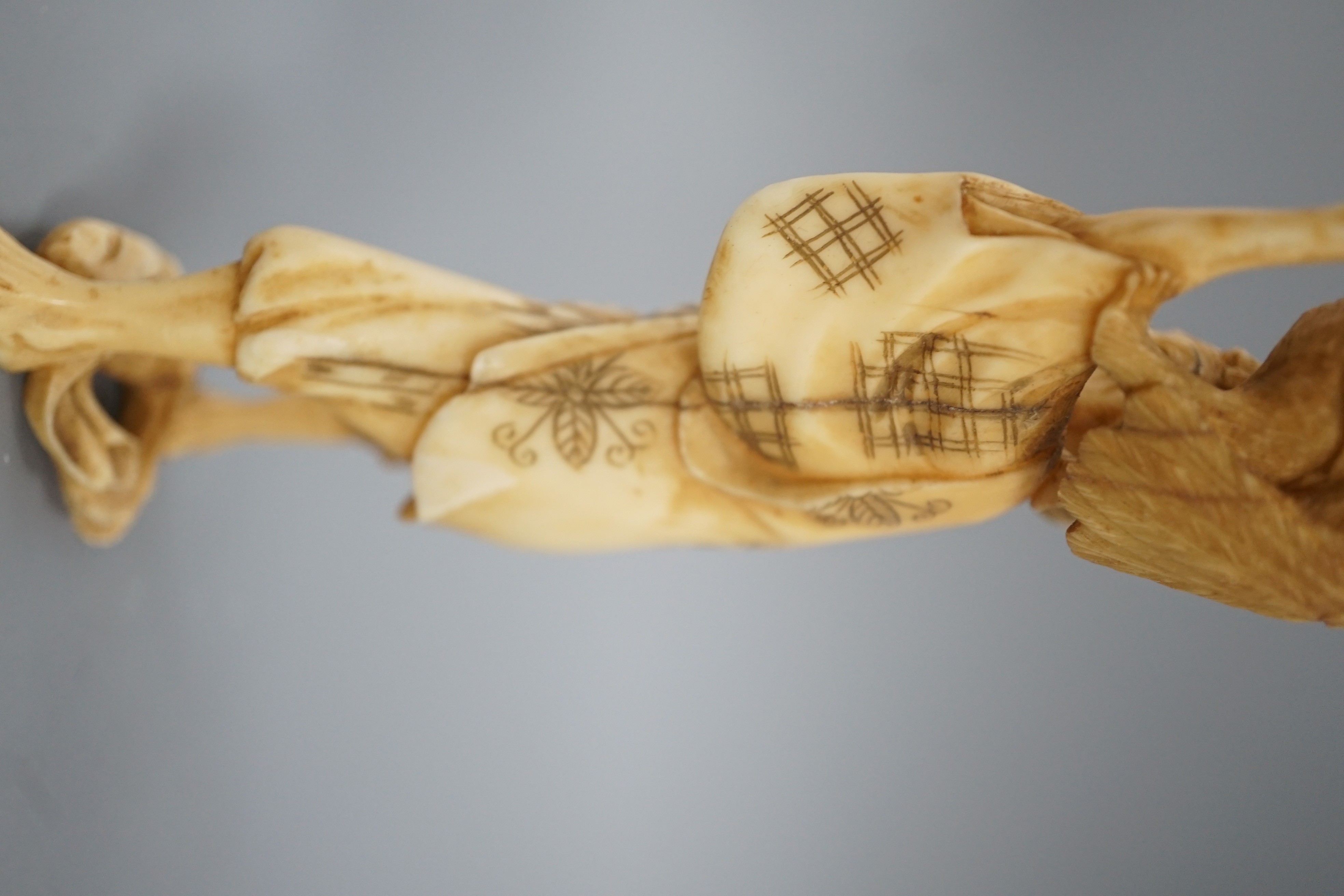 A Japanese ivory okimono of a man holding a monkey which is being attacked by an eagle, early 20th century 15.5cm